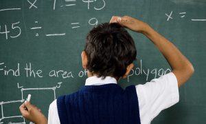 boy at chalkboard doing math formulas and scratching head